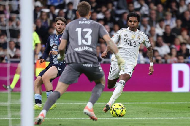 Real Madrid's Brazilian forward #11 Rodrygo runs with the ball challenged by Celta Vigo's Romanian goalkeeper #13 Ionut Andrei Radu during the Spanish league football match between Real Madrid CF and RC Celta de Vigo at the Santiago Bernabeu Stadium in Madrid on December 7, 2025. (Photo by Thomas COEX / AFP)