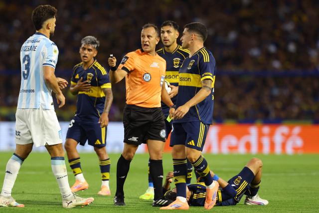 Referee Dario Herrera (C) talks to Racing's defender #03 Marco Di Cesare during the Argentine Professional Football League 2025 Clausura Tournament semifinal match between Boca Juniors and Racing at La Bombonera Stadium in Buenos Aires on December 7, 2025. (Photo by ALEJANDRO PAGNI / AFP)