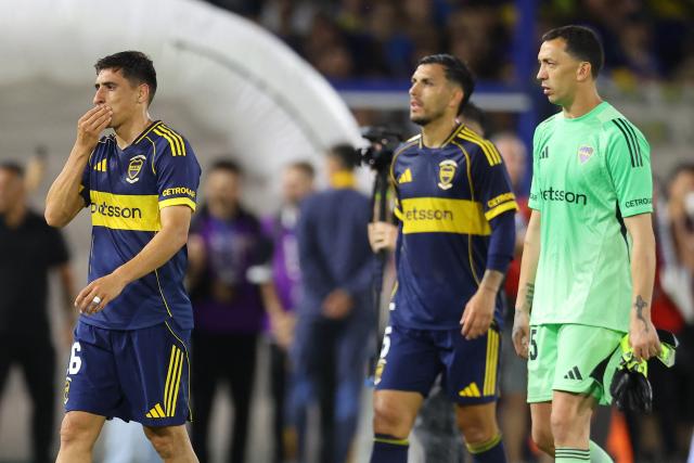 Boca Juniors' Uruguayan forward #16 Miguel Merentiel (L), midfielder #05 Leandro Paredes (C), and goalkeeper #25 Agustin Marchesin leave the pitch after losing the Argentine Professional Football League 2025 Clausura Tournament semifinal match between Boca Juniors and Racing at La Bombonera Stadium in Buenos Aires on December 7, 2025. (Photo by ALEJANDRO PAGNI / AFP)