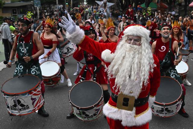 An artist in a Santa Claus costume takes part in a Christmas parade in Bogota on December 7, 2025. (Photo by Raul ARBOLEDA / AFP)