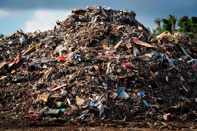 This photograph shows a plot of land filled with debris from houses and metal sheets following the 2024 Cyclone Chido, in Mamoudzou, on the French Indian Ocean territory of Mayotte, on December 2, 2025. Chido, the most devastating cyclone to hit Mayotte in the last 90 years, hit France's poorest department on December 14, 2024, causing colossal damage. (Photo by Marine GACHET / AFP)