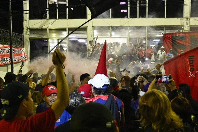 Supporters of Honduran presidential candidate Rixi Moncada of the ruling Libertad y Refundacion (LIBRE) party shout slogans outside the Libre Party branch in Tegucigalpa on December 7, 2025. The ruling Libre party rejected Honduras’s presidential elections on Sunday over alleged U.S. ‘interference,’ while the release of the vote count remained stalled for the second consecutive day, according to various sources. (Photo by Orlando SIERRA / AFP)
