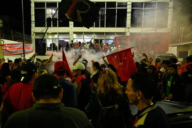 Supporters of Honduran presidential candidate Rixi Moncada of the ruling Libertad y Refundacion (LIBRE) party shout slogans outside the Libre Party branch in Tegucigalpa on December 7, 2025. The ruling Libre party rejected Honduras’s presidential elections on Sunday over alleged U.S. ‘interference,’ while the release of the vote count remained stalled for the second consecutive day, according to various sources. (Photo by Orlando SIERRA / AFP)