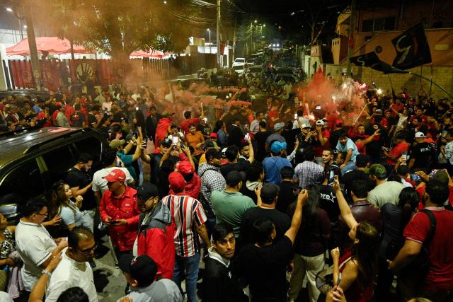Supporters of Honduran presidential candidate Rixi Moncada of the ruling Libertad y Refundacion (LIBRE) party shout slogans outside the Libre Party branch in Tegucigalpa on December 7, 2025. The ruling Libre party rejected Honduras’s presidential elections on Sunday over alleged U.S. ‘interference,’ while the release of the vote count remained stalled for the second consecutive day, according to various sources. (Photo by Orlando SIERRA / AFP)