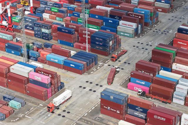 An aerial view shows trucks operating at the Shanghai Port container terminal in Shanghai on December 8, 2025. China's exports grew faster than expected last month, official data showed on December 8, returning to growth after sliding in October despite a sharp drop in shipments to the United States. (Photo by -STR / AFP) / China OUT
