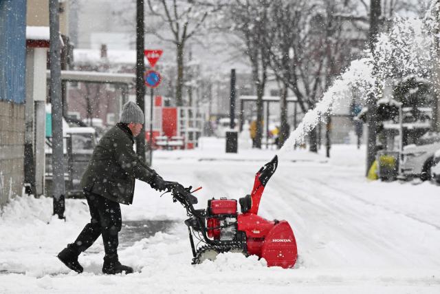 A man uses a snow blower to clear snow from a road in Chitose, in Japan’s northern Hokkaido prefecture on December 8, 2025. (Photo by GREG BAKER / AFP)