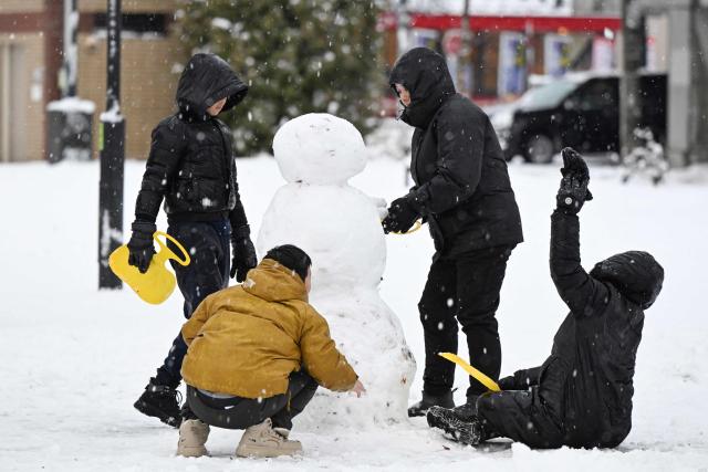 Tourists from Singapore make a snowman after snowfall at a park in Chitose, in Japan’s northern Hokkaido prefecture on December 8, 2025. (Photo by GREG BAKER / AFP)
