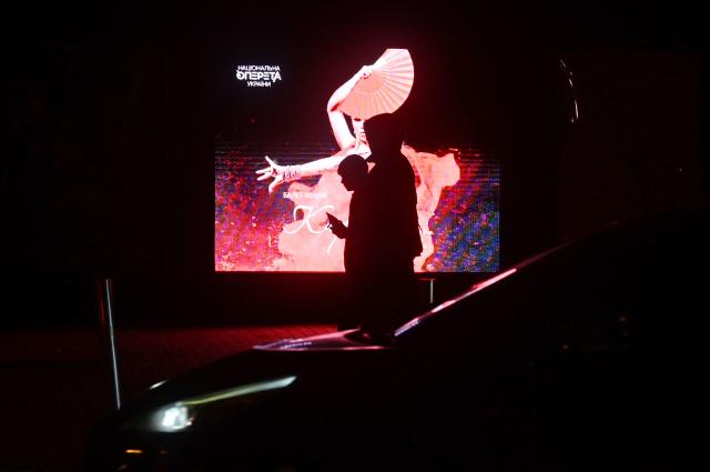 People walk past an advertising screen outside Kyiv Operetta Theater during blackout hours on December 7, 2025, amid the Russian invasion of Ukraine. (Photo by Sergei SUPINSKY / AFP)