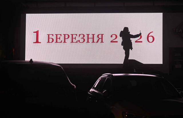 TOPSHOT - A girl makes a selfie in front of an advertising screen during blackout hours in Kyiv on December 7, 2025, amid the Russian invasion of Ukraine. (Photo by Sergei SUPINSKY / AFP)