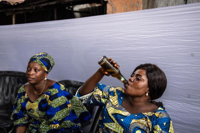 A guest enjoys a drink as she gathers with others for a diploma celebration party in Cotonou on December 7, 2025. (Photo by OLYMPIA DE MAISMONT / AFP)