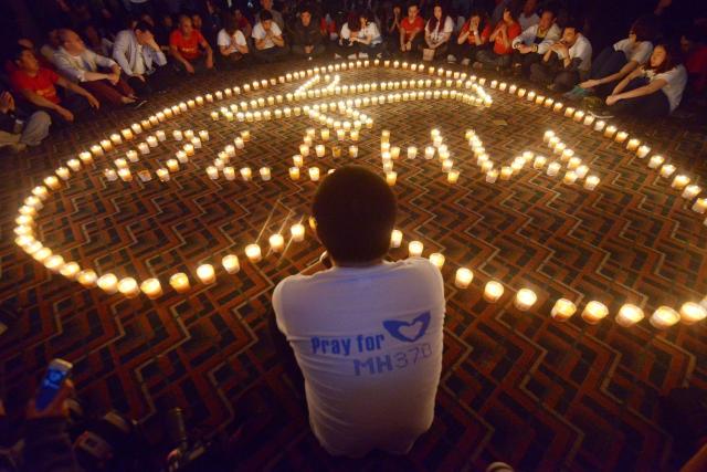 (FILES) Chinese relatives of passengers on the missing Malaysia Airlines flight MH370 take part in a prayer service at the Metro Park Hotel in Beijing on April 8, 2014. A Beijing court ordered Malaysia Airlines on December 8, 2025 to pay compensation to the families of eight passengers from flight MH370, more than a decade after the plane disappeared. (Photo by WANG Zhao / AFP)