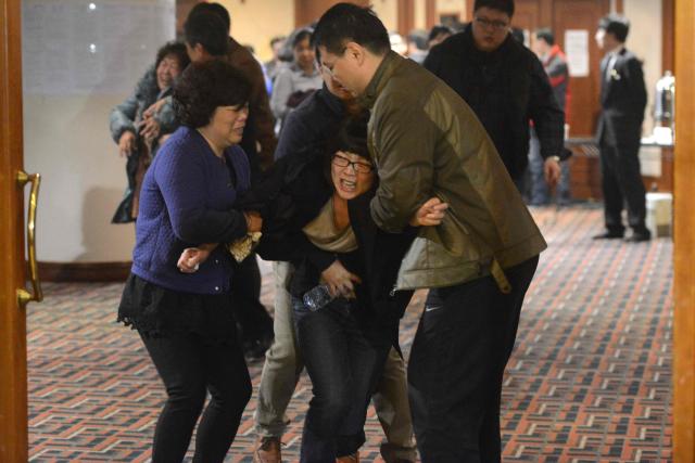 (FILES) Grieving relatives of passengers on Malaysia Airlines flight MH370 leave a hotel hall after being told the news that the plane plunged into Indian Ocean in Beijing on March 24, 2014. A Beijing court ordered Malaysia Airlines on December 8, 2025 to pay compensation to the families of eight passengers from flight MH370, more than a decade after the plane disappeared. (Photo by GOH CHAI HIN / AFP)