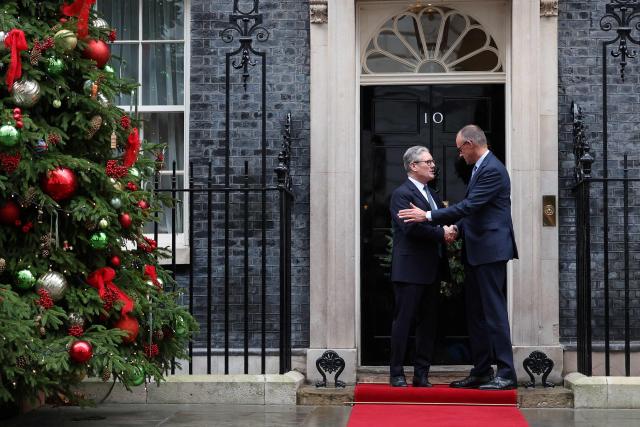 Britain's Prime Minister Keir Starmer (L) welcomes Germany's Chancellor Friedrich Merz (R) upon his arrival at Number 10 Downing Street in central London on December 8, 2025, as the leaders of Britain, France, Germany and Ukraine meet for talks. (Photo by Toby Melville / POOL / AFP)