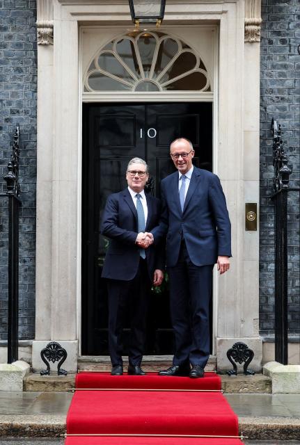 Britain's Prime Minister Keir Starmer (L) welcomes Germany's Chancellor Friedrich Merz (R) upon his arrival at Number 10 Downing Street in central London on December 8, 2025, as the leaders of Britain, France, Germany and Ukraine meet for talks. (Photo by Toby Melville / POOL / AFP)