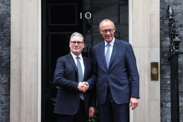 Britain's Prime Minister Keir Starmer (L) welcomes Germany's Chancellor Friedrich Merz (R) upon his arrival at Number 10 Downing Street in central London on December 8, 2025, as the leaders of Britain, France, Germany and Ukraine meet for talks. (Photo by Toby Melville / POOL / AFP)
