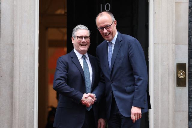 Britain's Prime Minister Keir Starmer (L) welcomes Germany's Chancellor Friedrich Merz (R) upon his arrival at Number 10 Downing Street in central London on December 8, 2025, as the leaders of Britain, France, Germany and Ukraine meet for talks. (Photo by Toby Melville / POOL / AFP)