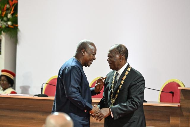 Ivory Coast President Alassane Ouattara (R) is congratulated by Ghana’s President John Mahama (L) at the Presidential Palace in Abidjan on December 8, 2025. (Photo by SIA KAMBOU / POOL / AFP)