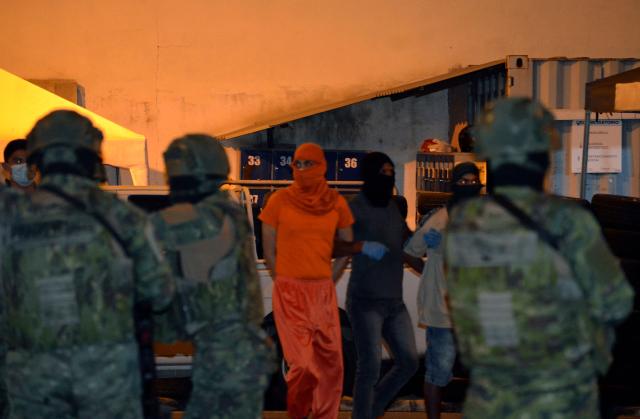 Members of the armed forces escort two inmates to a truck after several bodies were found during a police inspection, outside Machala prison in Machala, Ecuador, on December 7, 2025. At least thirteen inmates were found dead from "asphyxiation" in an Ecuadorian prison, moments after a drone loaded with explosives went off to distract the officers guarding the facility, the prison authority said. (Photo by Luis SUAREZ / AFP)
