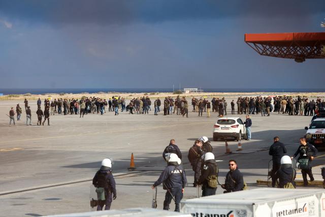 Farmers stand on the tarmac at Heraklion International Airport during a demonstration in Heraklion, on the island of Crete, on December 8, 2025. Farmers on Crete on Monday clashed with riot police near the Greek island's international airports in a burgeoning protest wave related to an EU subsidy probe. (Photo by Costas METAXAKIS / AFP)