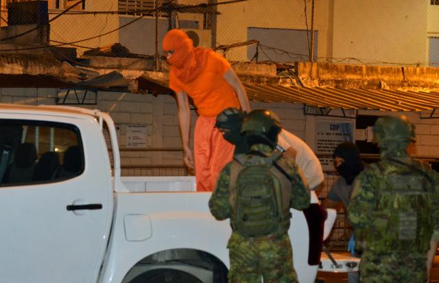 Members of the armed forces escort two inmates to a truck after several bodies were found during a police inspection, outside Machala prison in Machala, Ecuador, on December 7, 2025. At least thirteen inmates were found dead from "asphyxiation" in an Ecuadorian prison, moments after a drone loaded with explosives went off to distract the officers guarding the facility, the prison authority said. (Photo by Luis SUAREZ / AFP)