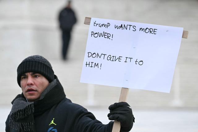 A demonstrator holds up a sign outside the US Supreme Court as the Court hears arguments in the case over President Donald Trump's dismissal of Federal Trade Commission (FTC) commissioner Rebecca Slaughter last March in Washington, DC, on December 8, 2025. The case is being closely watched due to its broader implications concerning President Trump's powers to fire the heads of independent government agencies. (Photo by Jim WATSON / AFP)