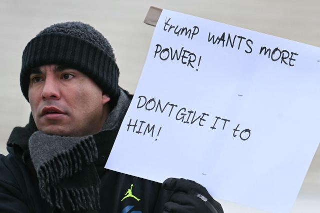 A demonstrator holds up a sign outside the US Supreme Court as the Court hears arguments in the case over President Donald Trump's dismissal of Federal Trade Commission (FTC) commissioner Rebecca Slaughter last March in Washington, DC, on December 8, 2025. The case is being closely watched due to its broader implications concerning President Trump's powers to fire the heads of independent government agencies. (Photo by Jim WATSON / AFP)