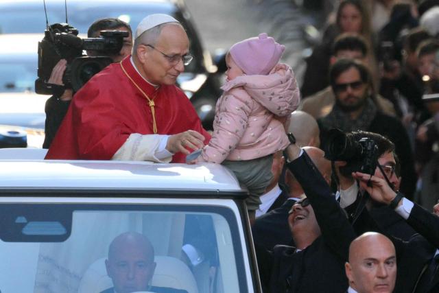 Pope Leo XIV blesses a baby presented to him on the popemobile in Via dei Condotti as he arrives to pay homage to the Immaculate Conception, near the Spanish steps in Rome, on December 8, 2025. (Photo by Tiziana FABI / AFP)