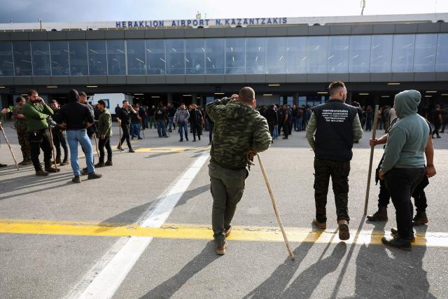 Farmers stand at Heraklion International Airport during a demonstration in Heraklion, on the island of Crete, on December 8, 2025. Farmers on Crete on Dcemeber 5 clashed with riot police near the Greek island's international airports in a burgeoning protest wave related to an EU subsidy probe. (Photo by Costas METAXAKIS / AFP)