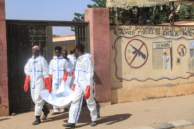 Employees working for the authorities carry away a body bag as the exhumation and transfer of bodies from emergency burial sites inside schools, are taken to public cemeteries for burial, in the capital Khartoum on December 8, 2025. (Photo by Ebrahim Hamid / AFP)