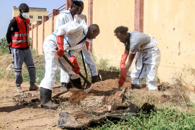 Employees working for the authorities dig as they exhume bodies to be transferred from an emergency burial site inside a school, to public cemeteries for burial, in the capital Khartoum on December 8, 2025. (Photo by Ebrahim Hamid / AFP)