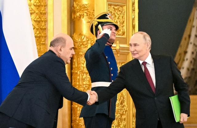 In this pool photograph distributed by the Russian state agency Sputnik, Russia's President Vladimir Putin shakes hands with Prime Minister Mikhail Mishustin during a meeting of the Council for Strategic Development and National Projects at the Kremlin in Moscow on December 8, 2025. (Photo by Kristina Kormilitsyna / POOL / AFP)