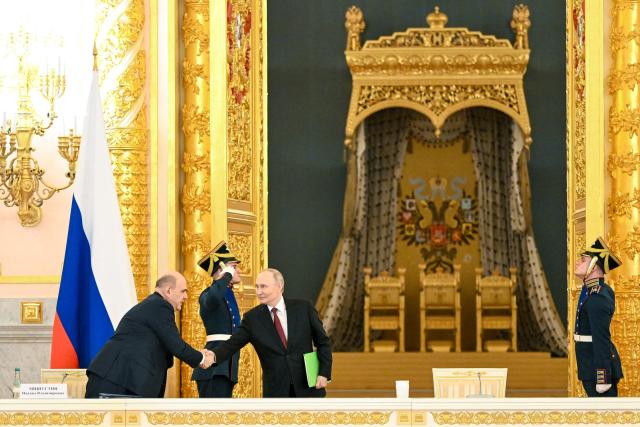 In this pool photograph distributed by the Russian state agency Sputnik, Russia's President Vladimir Putin shakes hands with Prime Minister Mikhail Mishustin during a meeting of the Council for Strategic Development and National Projects at the Kremlin in Moscow on December 8, 2025. (Photo by Kristina Kormilitsyna / POOL / AFP)