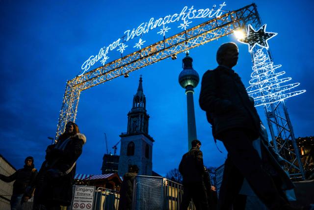 Visitors enter a traditional Christmas market in front of the town hall (Rote Rathaus), and the TV tower, in Berlin, Germany, on December 8, 2025. (Photo by John MACDOUGALL / AFP)