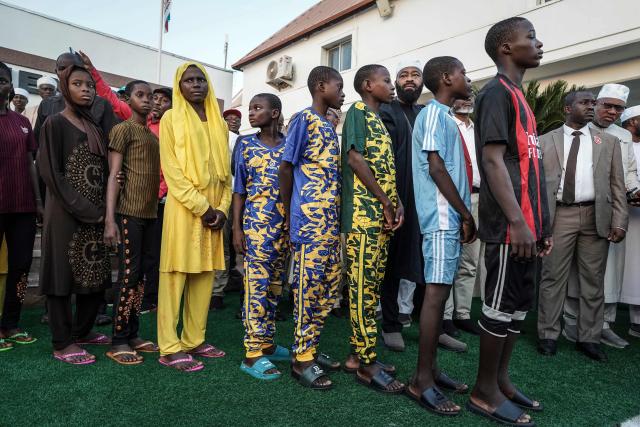 TOPSHOT - Schoolchildren arrive at the local governor's office in Minna on December 8, 2025. Around a hundred schoolchildren who were abducted last month by armed men from a Catholic school have arrived at the government headquarters in Minna, the capital of Niger State in central-northern Nigeria, as observed by AFP journalists on Monday. However, the fate of the 165 others abducted with them remains unknown. The students, mostly aged between 10 and 17, arrived in five white buses escorted by about ten military and armored vehicles and were received by Niger State Governor Mohammed Umaru Bago. (Photo by Light Oriye Tamunotonye / AFP)