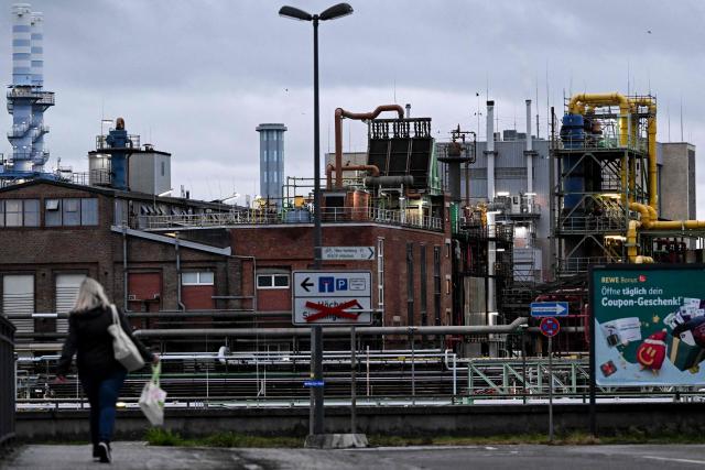 A woman walks past an industrial area with chemical plants in Frankfurt am Main, western Germany, on December 8, 2025. (Photo by Kirill KUDRYAVTSEV / AFP)