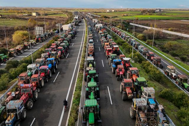 TOPSHOT - An aerial view shows tractors of farmers blocking the national highway outside the central Greek city of Karditsa on December 8, 2025 to demand swifter access to EU subsidies. Greek farmers demanding the payment of EU subsidies on December 8 shut down the two main international airports on the island of Crete after clashing with riot police in a growing showdown with the government. (Photo by Aris MESSINIS / AFP)