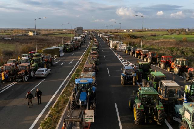 An aerial view shows tractors of farmers blocking the national highway outside the central Greek city of Karditsa on December 8, 2025 to demand swifter access to EU subsidies. Greek farmers demanding the payment of EU subsidies on December 8 shut down the two main international airports on the island of Crete after clashing with riot police in a growing showdown with the government. (Photo by Aris MESSINIS / AFP)