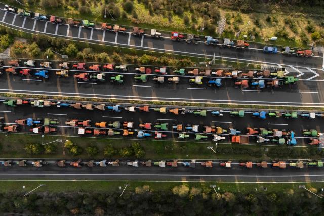 TOPSHOT - An aerial view shows tractors of farmers blocking the national highway outside the central Greek city of Karditsa on December 8, 2025 to demand swifter access to EU subsidies. Greek farmers demanding the payment of EU subsidies on December 8 shut down the two main international airports on the island of Crete after clashing with riot police in a growing showdown with the government. (Photo by Aris MESSINIS / AFP)