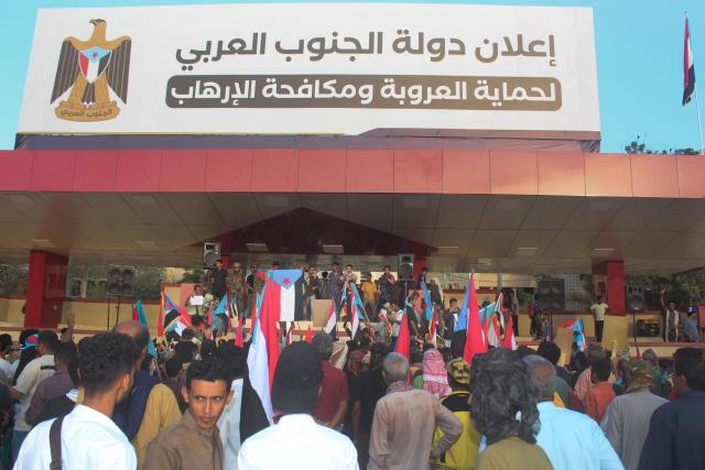 A sign reads, "Announcing the formation of south arabia nation to protect Arabs and counter terrorism" as Yemenis supporters of the UAE-backed Southern Transitional Council (STC), which wants to revive an independent South Yemen, hold the old South Yemen flag, as they rally in Al-Aroud Square demanding a "second independence", in the coastal port city of Aden on December 8, 2025. The STC is part of the internationally recognised government, which is a patchwork of groups held together by their opposition to Yemen's Houthi rebels. The Houthis hold most of the country's populated areas, including the capital Sanaa, in the north and west of the country. (Photo by Saleh Al-OBEIDI / AFP)