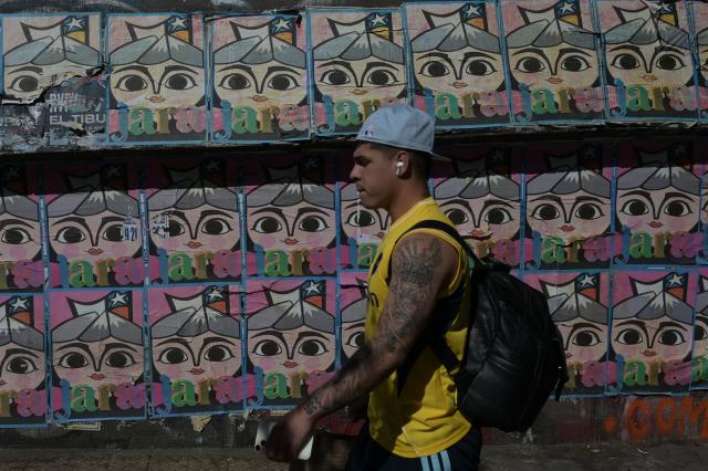 A pedestrian walks past posters supporting Chilean presidential candidate Jeannette Jara of the Unidad por Chile coalition in Santiago on December 8, 2025. Chile will choose its next president in a runoff on December 14, 2025, with far-right candidate Jose Antonio Kast as the clear favorite against leftist Jeannette Jara, after a campaign marked by fears over crime and irregular migrants. (Photo by Eitan ABRAMOVICH / AFP)