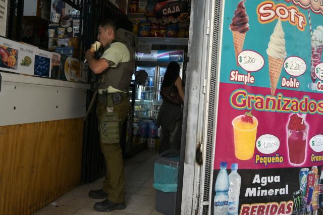 A Carabinero police officer buys an ice cream at a shop in Santiago's Lastarria neighborhood on December 8, 2025. Chile will choose its next president in a runoff on December 14, 2025, with far-right candidate Jose Antonio Kast as the clear favorite against leftist Jeannette Jara, after a campaign marked by fears over crime and irregular migrants. (Photo by Eitan ABRAMOVICH / AFP)