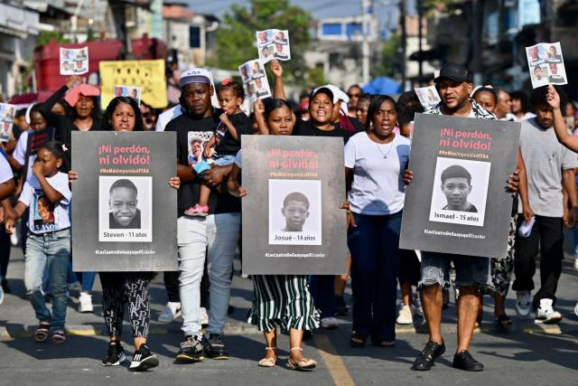 Relatives of the four minors apprehended by soldiers and found dead near a military base, hold their pictured during a rally to demand justice a year after their apprehension in Guayaquil, Ecuador on December 8, 2025. (Photo by MARCOS PIN / AFP)