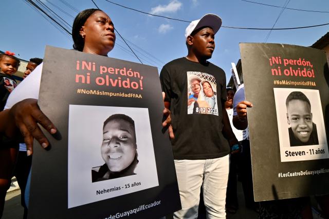 Relatives of the four minors apprehended by soldiers and found dead near a military base, hold their pictures during a rally to demand justice a year after their apprehension in Guayaquil, Ecuador on December 8, 2025. (Photo by MARCOS PIN / AFP)