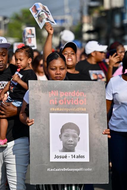 A woman hold the picture of one of the four minors apprehended by soldiers and found dead near a military base, during a rally to demand justice a year after their apprehension in Guayaquil, Ecuador on December 8, 2025. (Photo by MARCOS PIN / AFP)