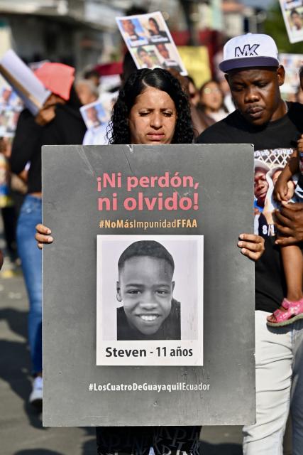 A woman hold the picture of one of the four minors apprehended by soldiers and found dead near a military base, during a rally to demand justice a year after their apprehension in Guayaquil, Ecuador on December 8, 2025. (Photo by MARCOS PIN / AFP)