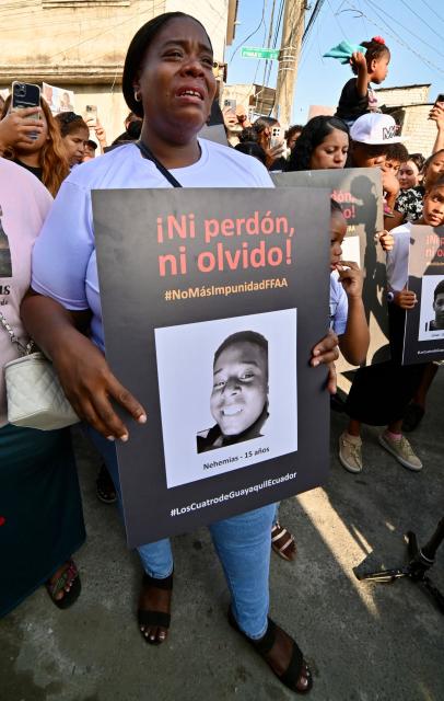 A woman cries as she holds the picture of one of the four minors apprehended by soldiers and found dead near a military base, during a rally to demand justice a year after their apprehension in Guayaquil, Ecuador on December 8, 2025. (Photo by MARCOS PIN / AFP)