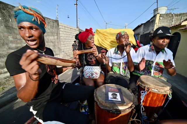 Relatives of the four minors apprehended by soldiers and found dead near a military base, play traditional music during a rally to demand justice a year after their apprehension in Guayaquil, Ecuador on December 8, 2025. (Photo by MARCOS PIN / AFP)