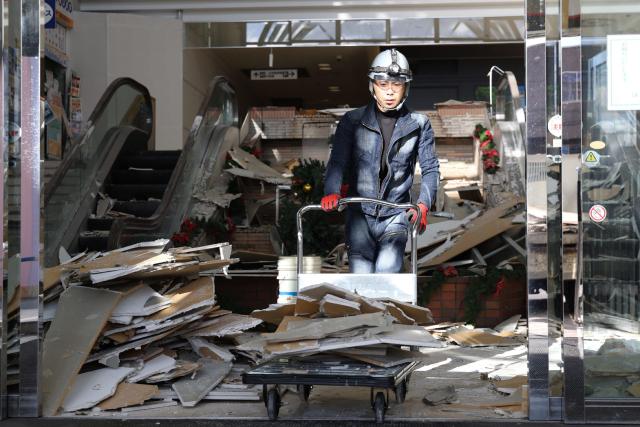 A worker clears debris at a shopping center damaged by the earthquake in Hachinohe City, Aomori Prefecture on December 9, 2025. (Photo by JIJI Press / AFP) / Japan OUT
