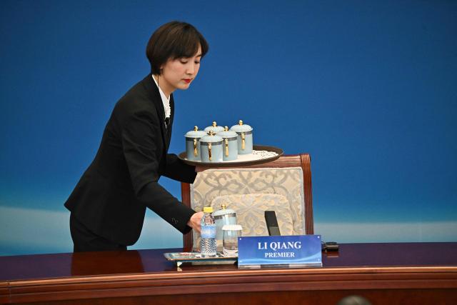 An attendee serves tea for the 1+10 Dialogue with leaders of International Economic Organisations in Beijing on December 9, 2025. (Photo by Pedro PARDO and Pedro Pardo / POOL / AFP)