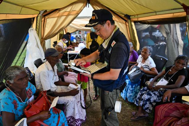 Japan Disaster Relief (JDR) medical officer tends to a flood victim at a camp in Chilaw on December 9, 2025. (Photo by Ishara S. KODIKARA / AFP)